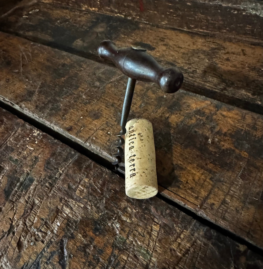Vintage corkscrew with cork on rustic wood