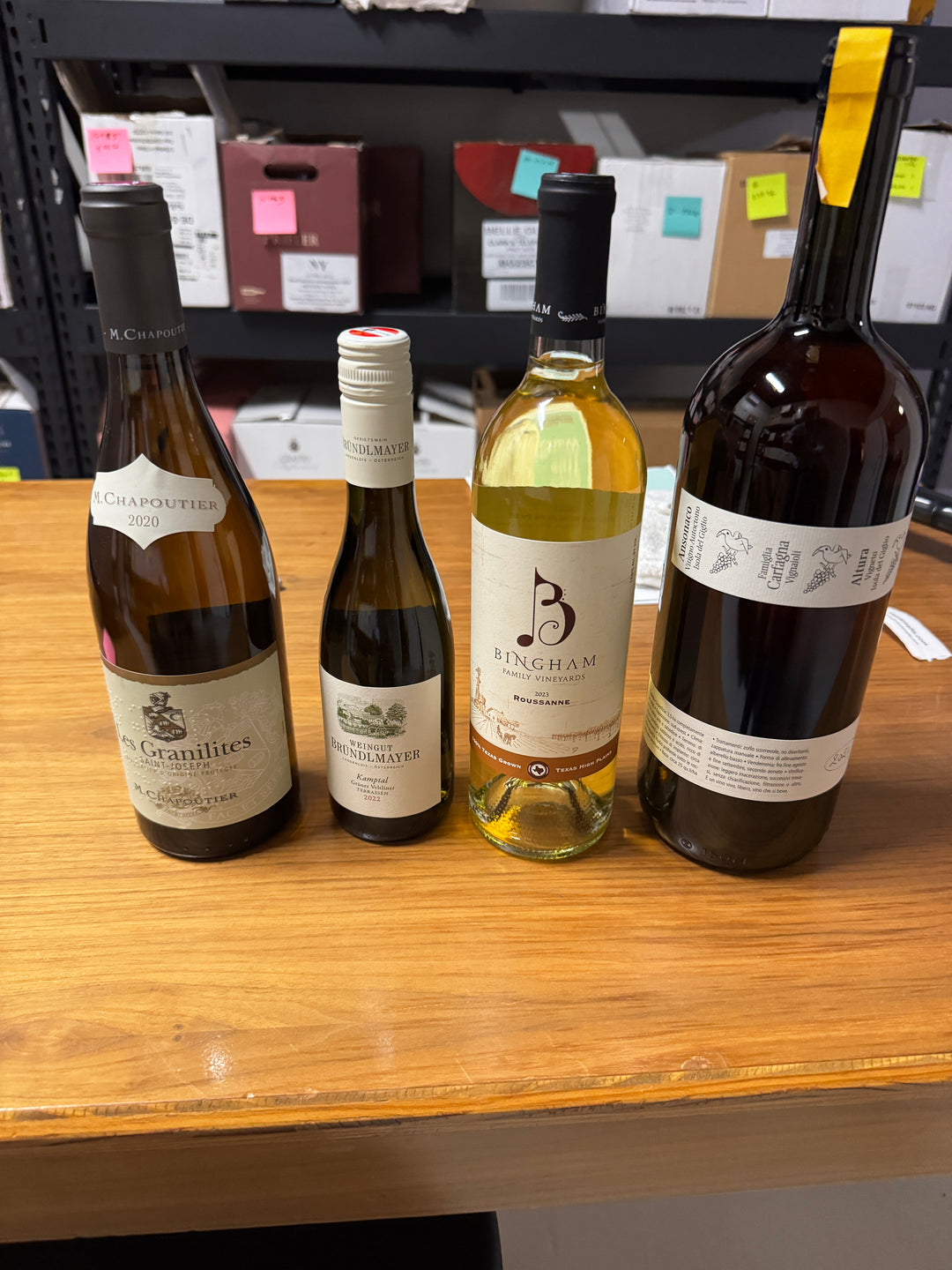 Four bottles of white wine from a past Munk Mafia Wine Club selection, including one magnum, lined up in warm light.