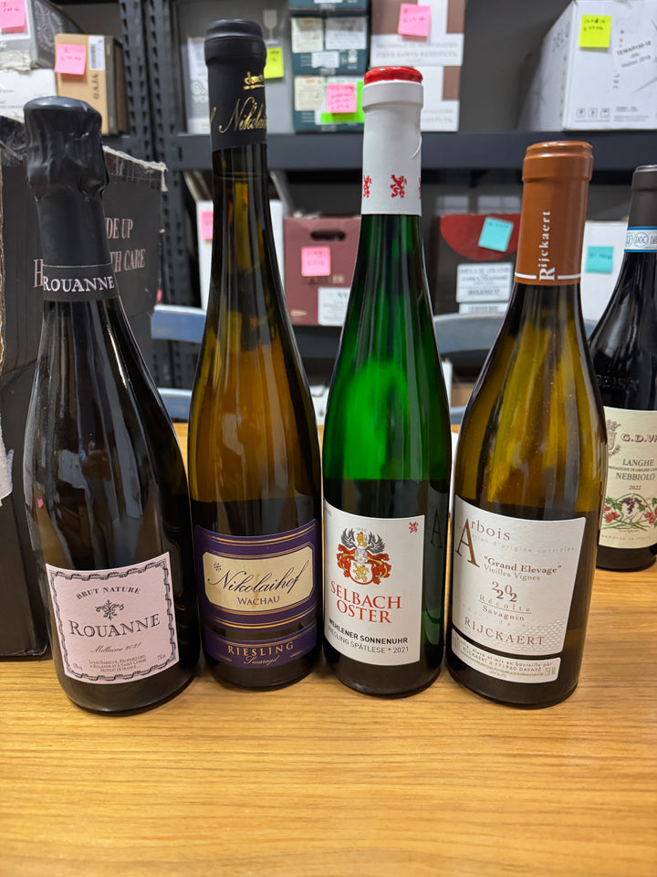 A past wine club selection of four bottles, including a sparkling rose, arranged in warm light.