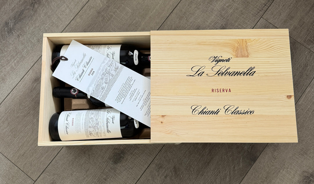 Open 6 pack wooden box of La Selvanella Chianti Classico DOCG red wine, etched top with winery name and leather tied wine information sheet showing on top of bottles.